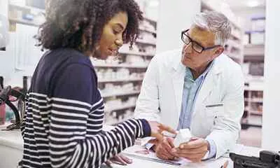 a person with a pharmacist pointing at a white box